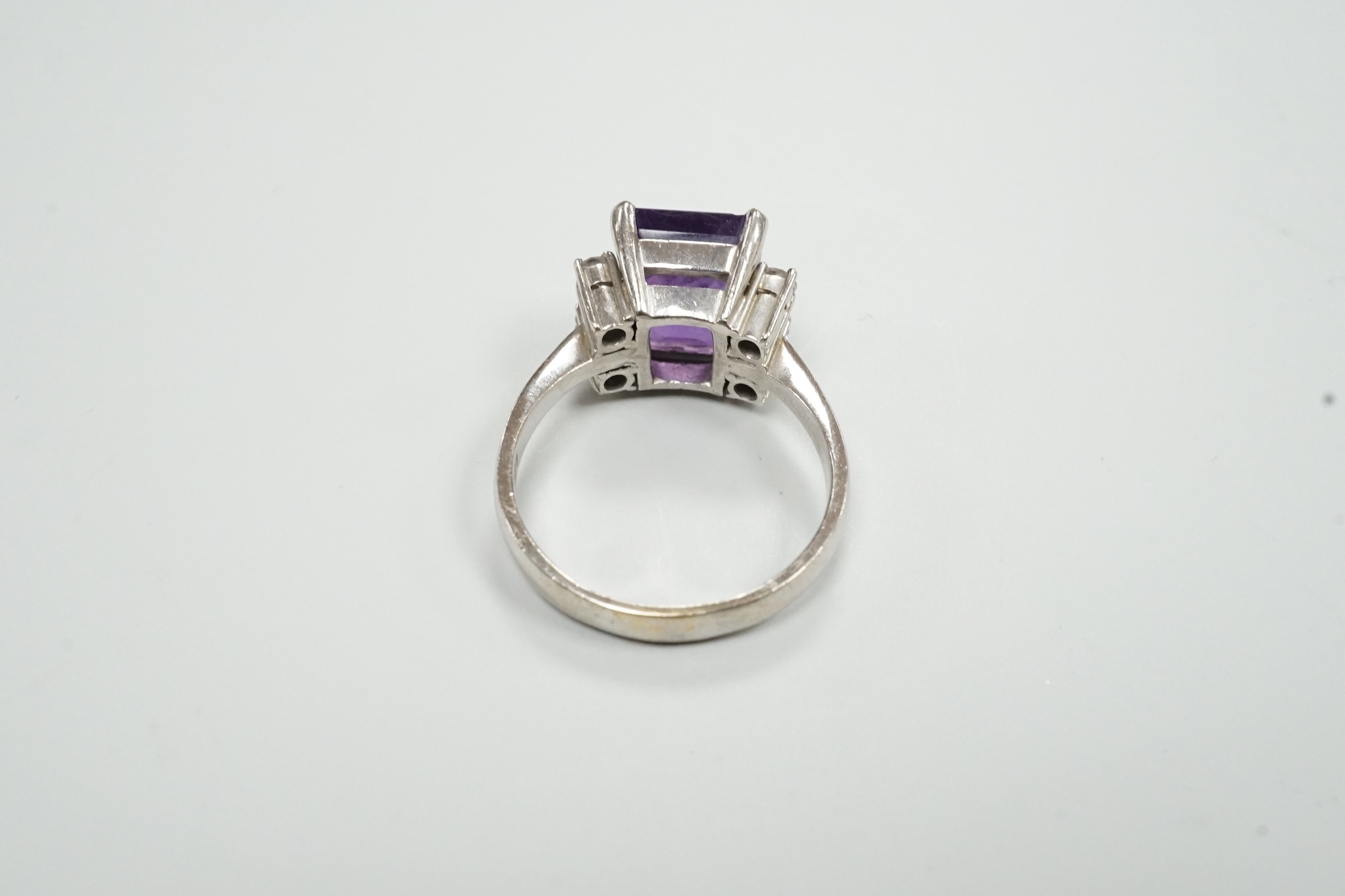 A modern 585 white metal single stone amethyst and four stone diamond set dress ring, size S/T, gross weight 8.1 grams.